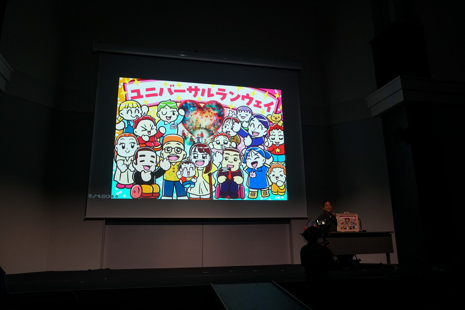 スクリーンに映された紙芝居のラストシーン。登場人物たちが「ユニバーサルランウェイ!」の文字とともに勢ぞろいしている。