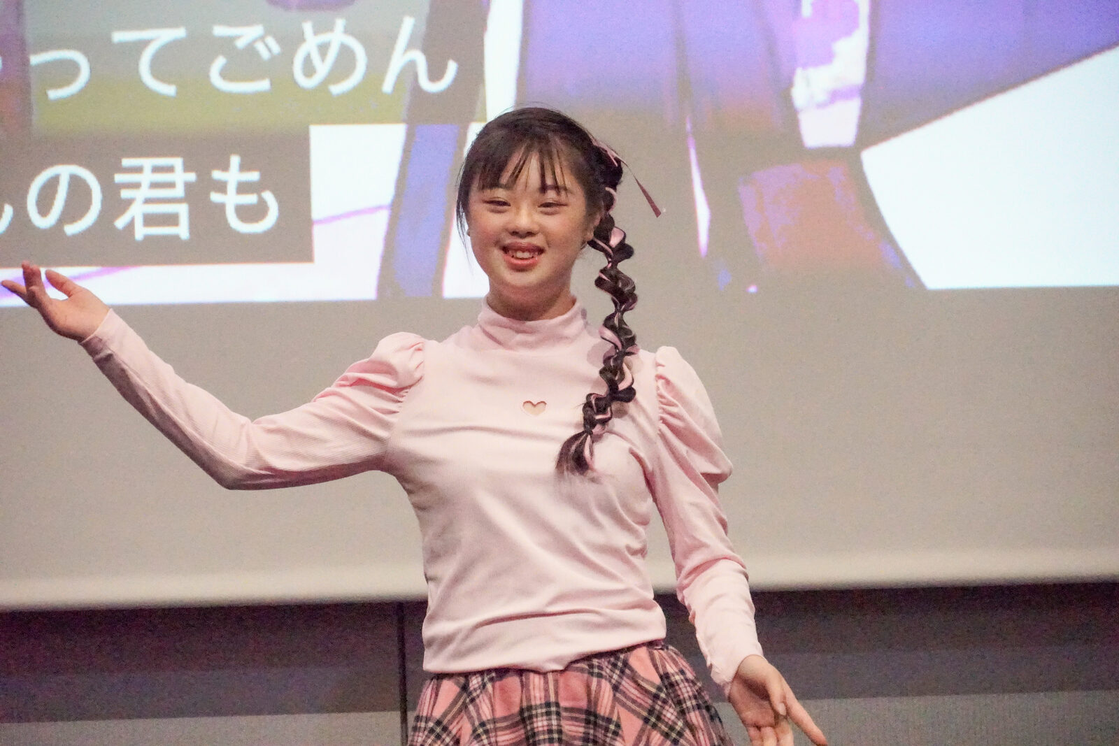 松浦由奈さんが両腕を大きく広げてダンスを踊っている。背後のスクリーンには楽曲の歌詞が流れる。