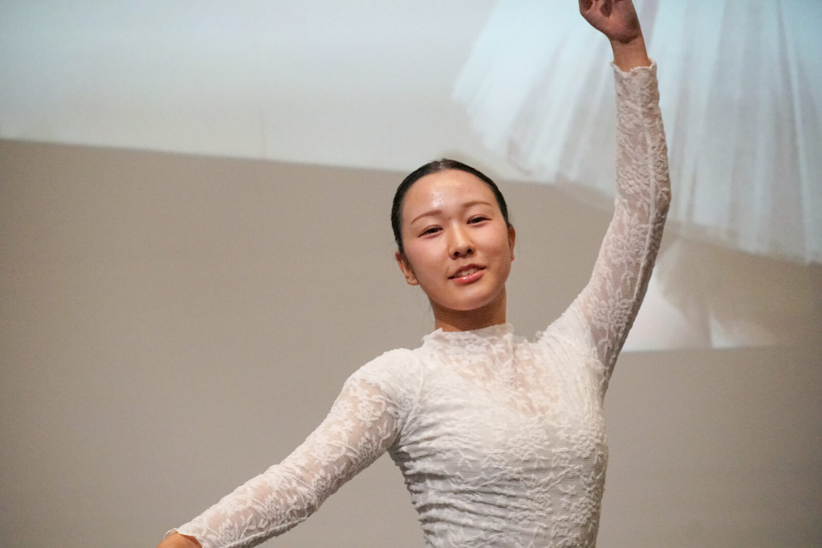 白いレースの衣装のバレリーナが、片腕を高く掲げたポーズで静止している。