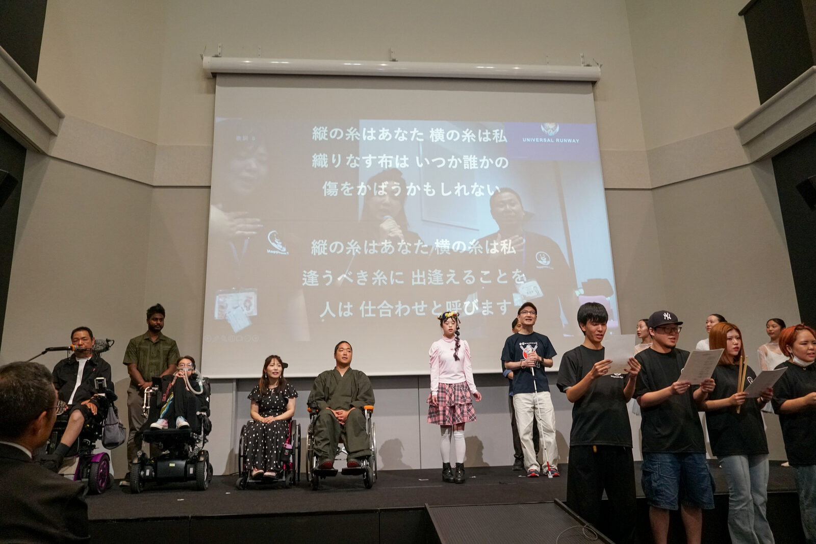 スクリーンに「糸」の歌詞が映され、その前に出演者たちが横一列に並んで歌っている。